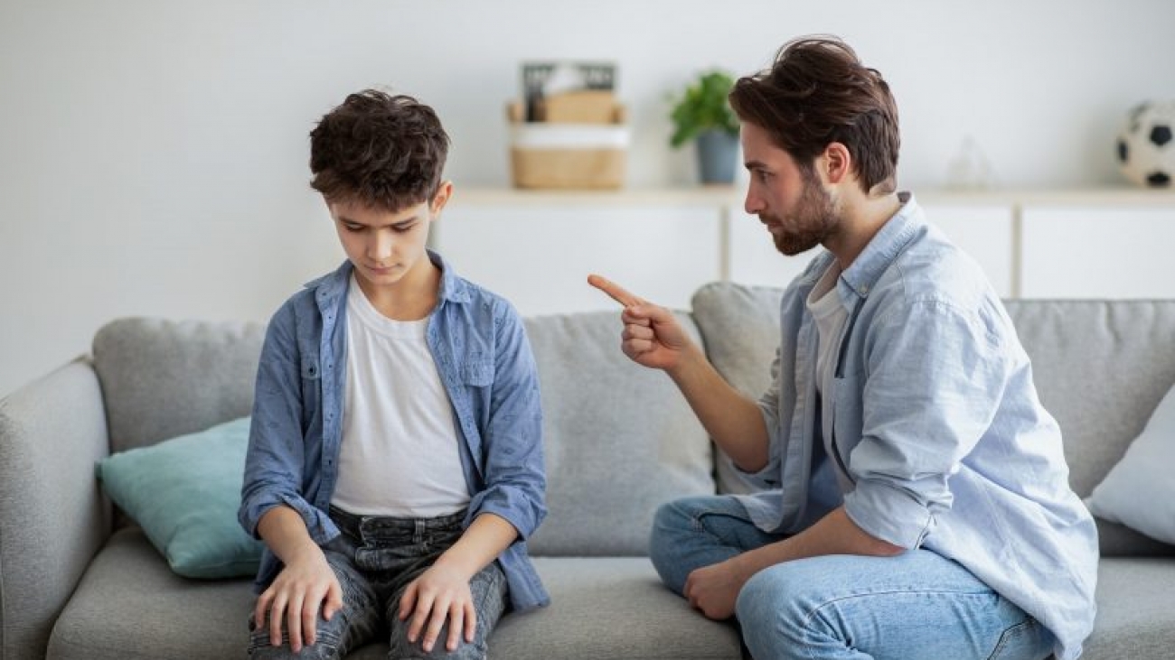 Family discipline concept. Grumpy dad scolding his offended son, teaching his kid tolerance, respect