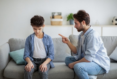 Family discipline concept. Grumpy dad scolding his offended son, teaching his kid tolerance, respect